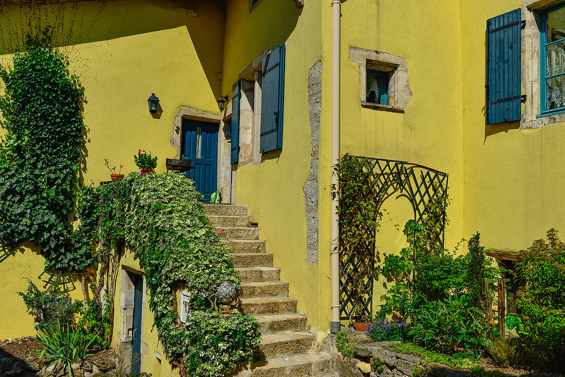 Üppiger Garten an einem gelben Haus mit blauen Fensterläden in Liverdun an der Mosel, Frankreich