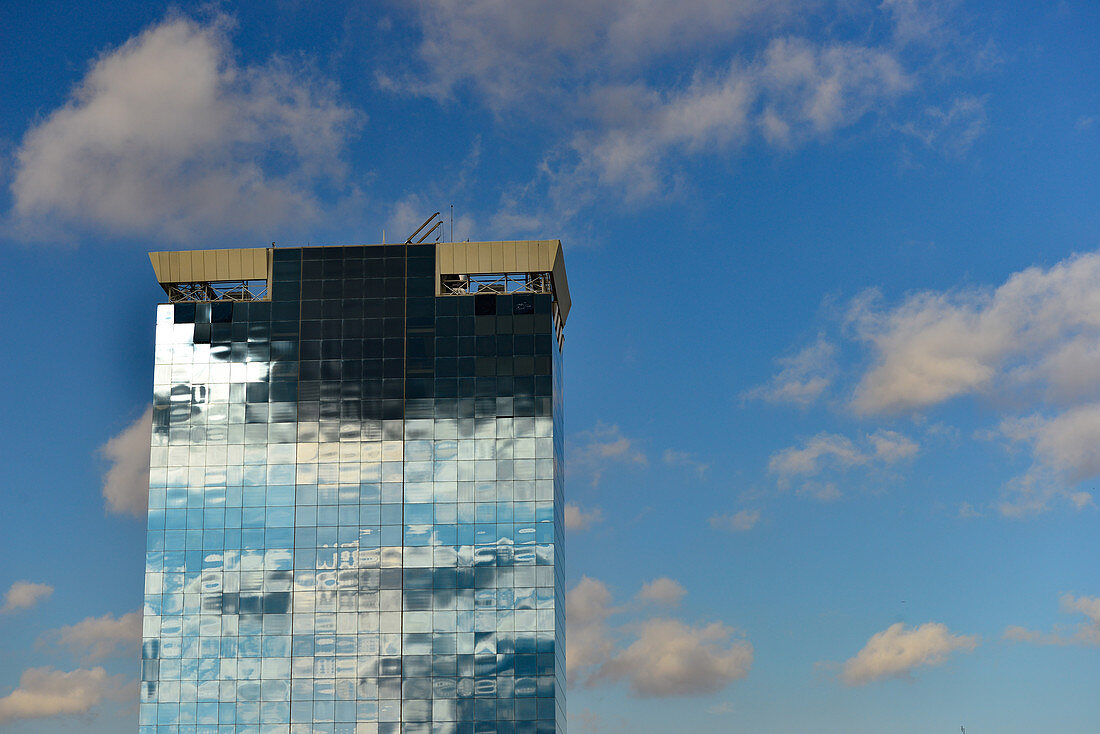 Hochhaus mit Glasfassade, die dunkle Wolken und intensives Licht spiegelt, Barcelona, Katalonien, Spanien