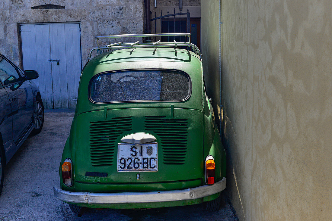 Parked Fiat 500 directly on a house wall, Sibenik, Adriatic Sea, Dalmatia, Croatia