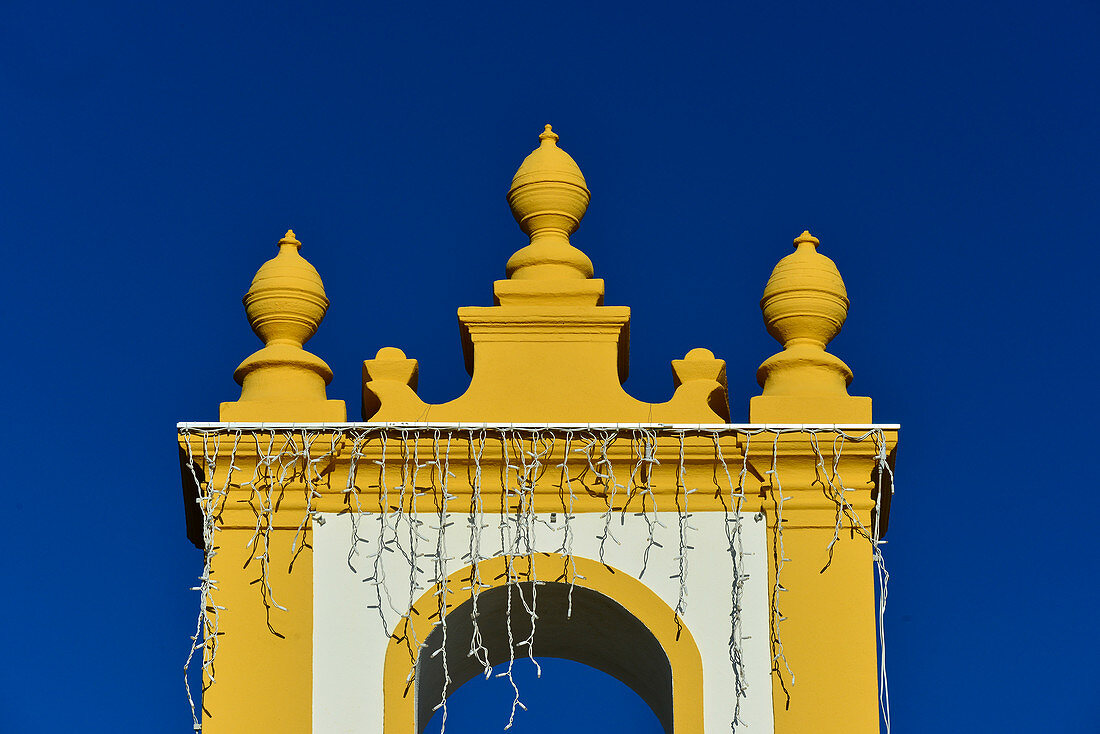 Blick auf die gelb-weiße Kirche mit Lichterkette, Luz, Algarve, Portugal