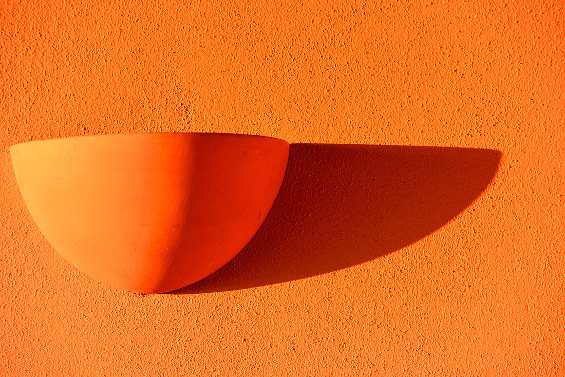 An orange lamp casts a shadow on an orange wall, Luz, Algarve, Portugal