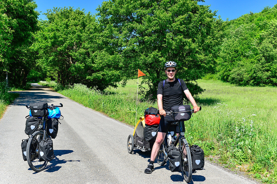 Cyclists on a long tour with full luggage and trailers on a lonely road near Breitenbrunn, Austria