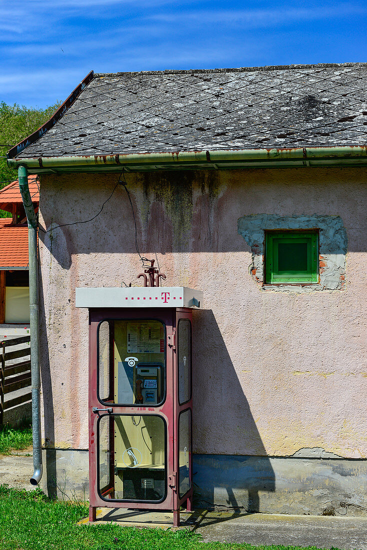 Eine alte Telefonzelle vor einem verfallenen Haus, Csöde, Ungarn