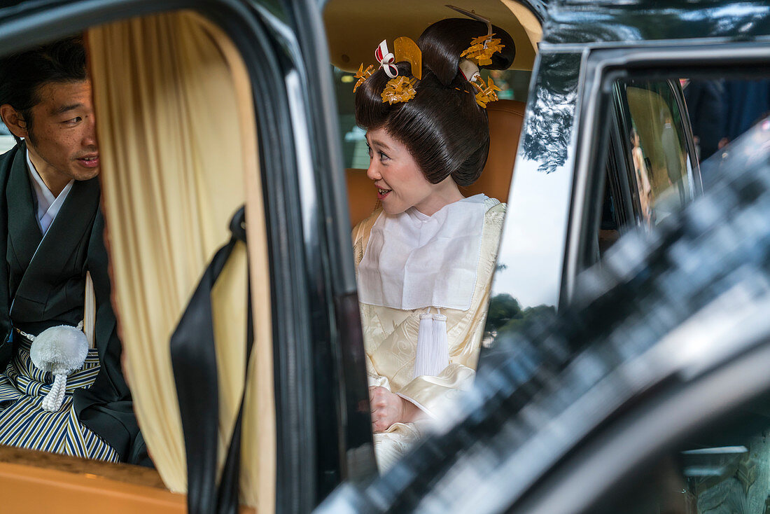 Frau in traditionellem Brautkleid im Auto mit Chauffeur, Tokio, Japan