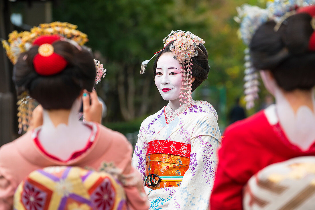 Women dressed in traditional geisha dress taking photograph, Kyoto, Japan