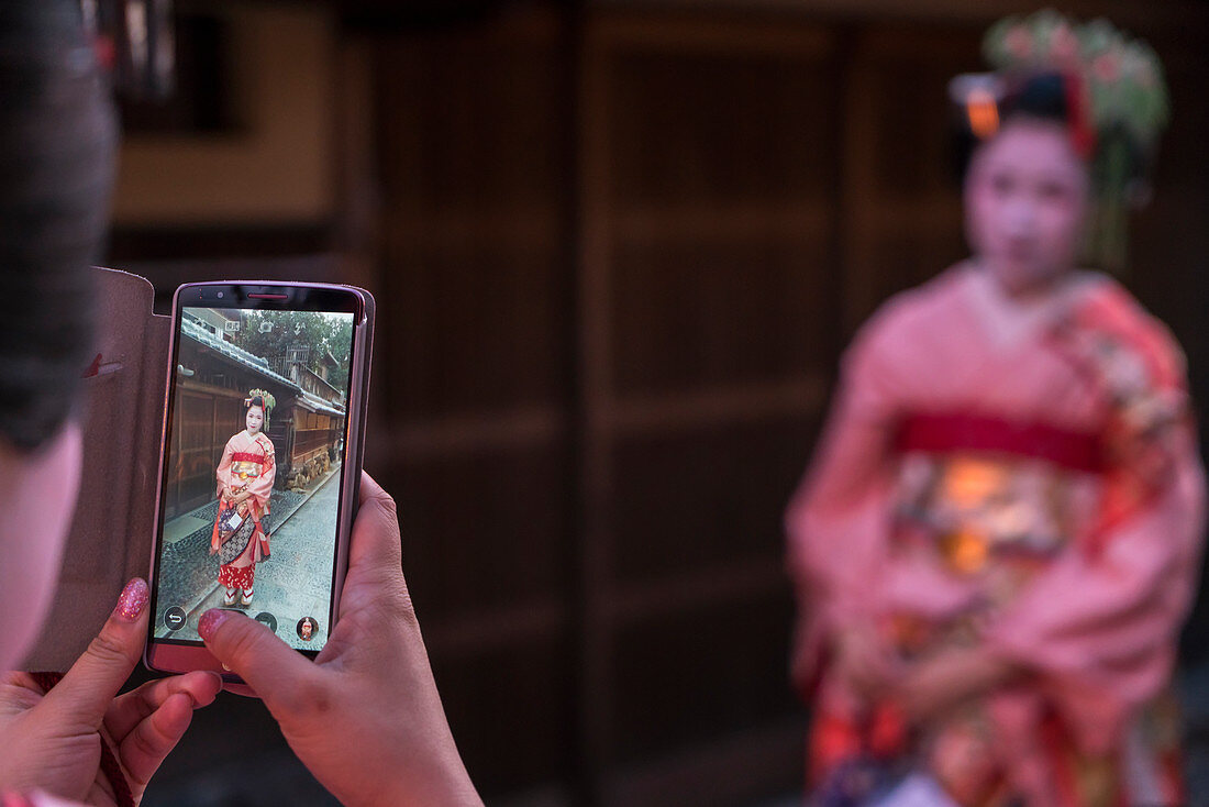 Frauen in traditioneller Geisha-Kleidung werden mit dem Mobiltelefon fotografiert