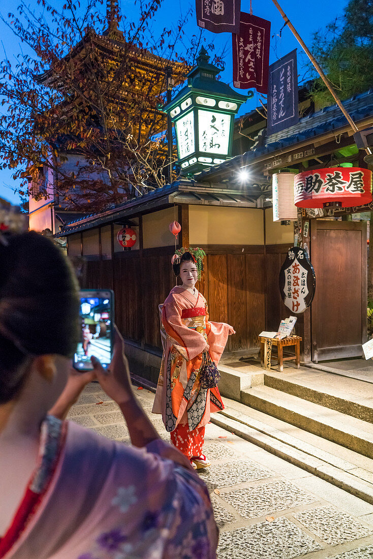 Frauen in traditioneller Geisha-Kleidung werden mit dem Mobiltelefon fotografiert, Kyoto, Japan