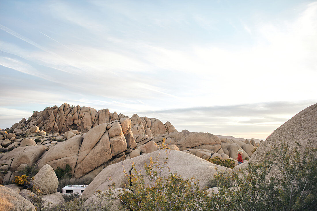 Rock formation with young child and camper in Joshua Tree Park, California, USA.