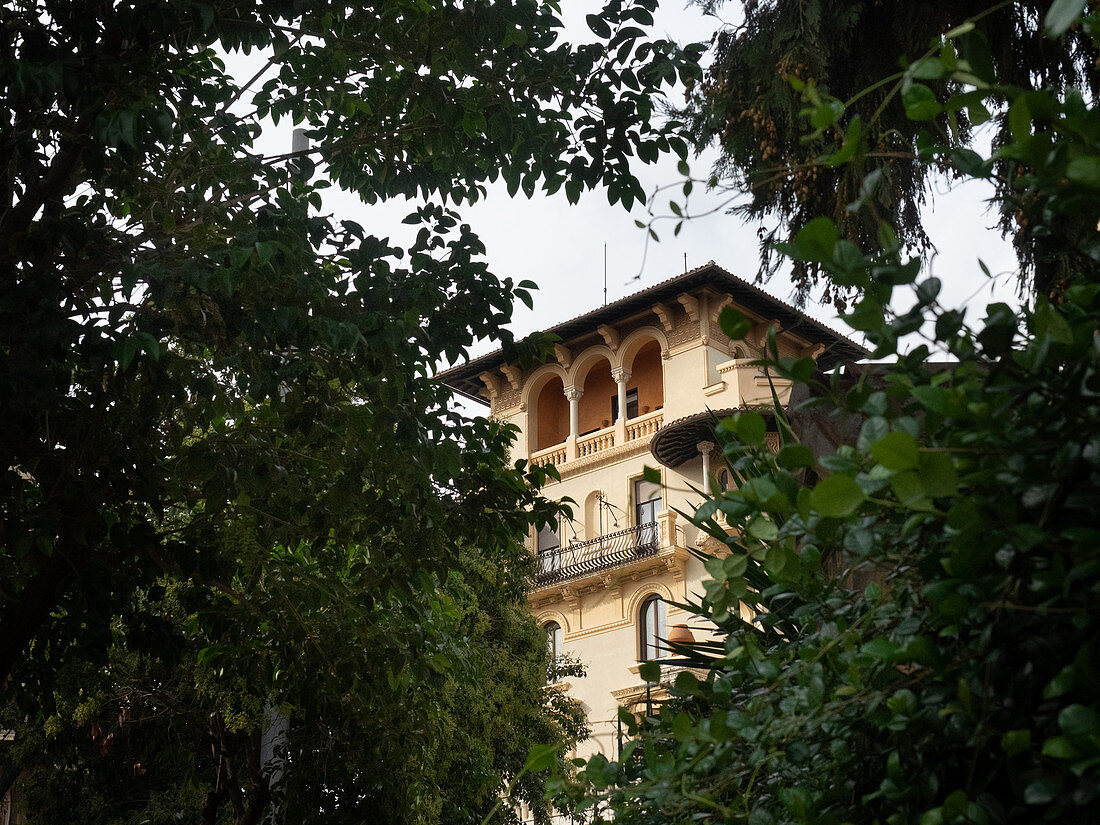 Quartiere Coppede, Rom, Italien: Turm von einem Gebäude, durch grüne Zweige von der Straße aus gesehen