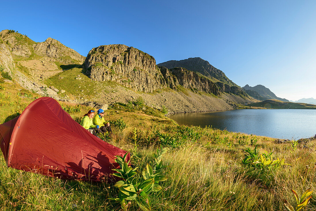 Mann und Frau sitzen bei Zelt am Lac Roumassot, Lac Roumassot, Nationalpark Pyrenäen, Pyrénées-Atlantiques, Pyrenäen, Frankreich