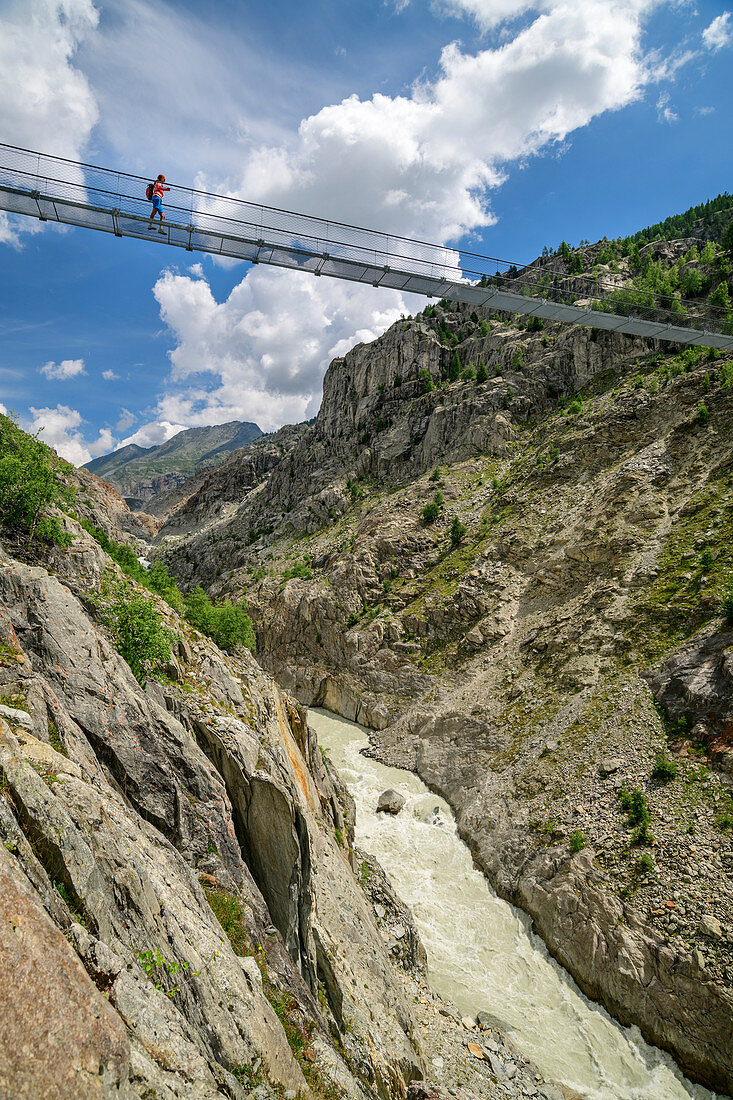 Frau beim Wandern geht über Aletsch-Hängebrücke, UNESCO Weltnaturerbe Jungfrau-Aletsch, Berner Alpen, Schweiz