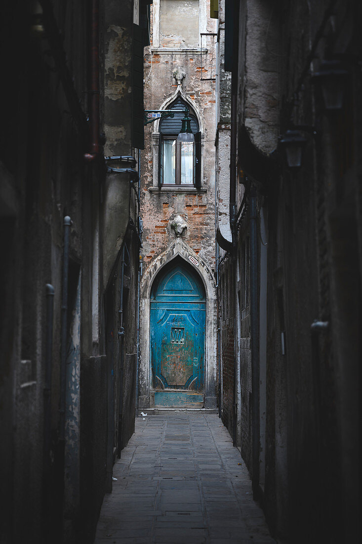 Eine kleine blaue Tür in einer sehr kleinen Straße in Venedig, Venetien, Italien.