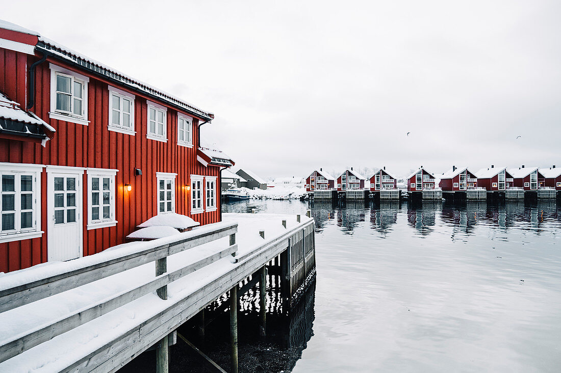 Rote Häuser am Wasser mit frischem Schnee in Svolvaer bedeckt. Lofoten, Nordland, Norwegen.