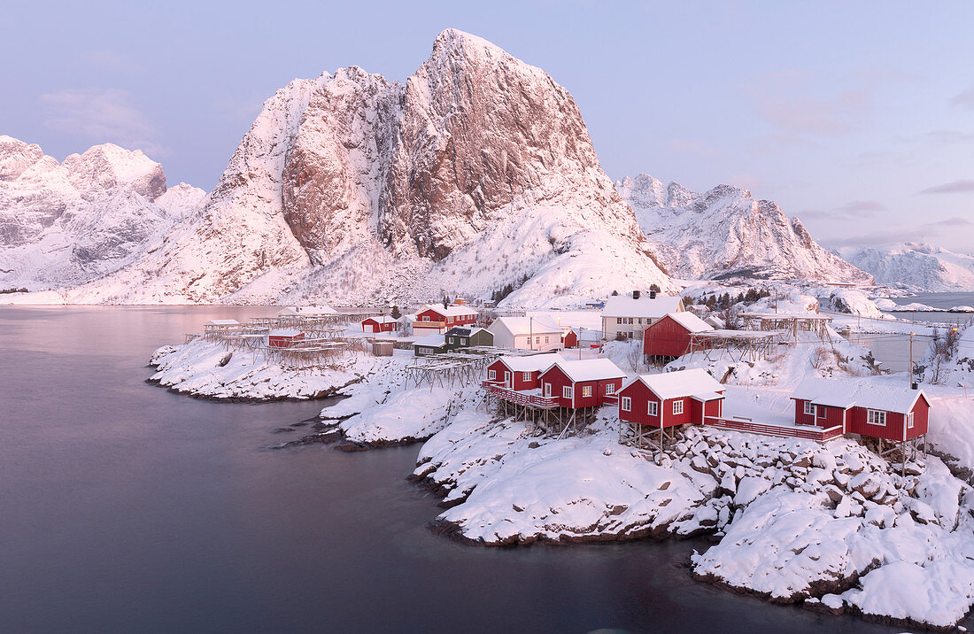 The snowy peaks and frozen sea frame the typical fisherman houses called Rorbu, Hamnøy, Lofoten Islands, Northern Norway, Europe