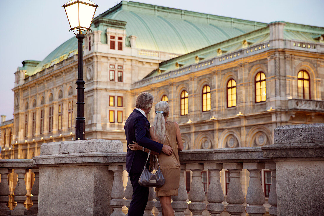 Rear view of a couple looking over a balustrade at a Vienna street.
