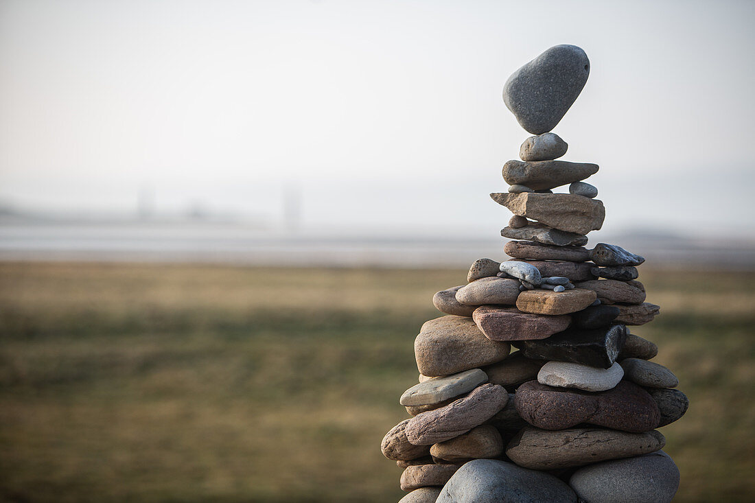 A tower of stones of various sizes stacked in a cairn, the top stone balancing on a point.