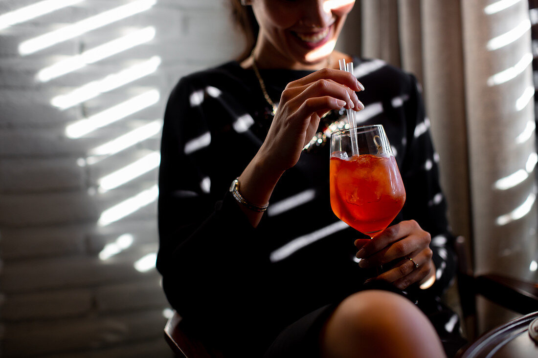 Glückliche junge Frau mit Aperol Spritz in einem Boutique-Hotelrestaurant, Italien