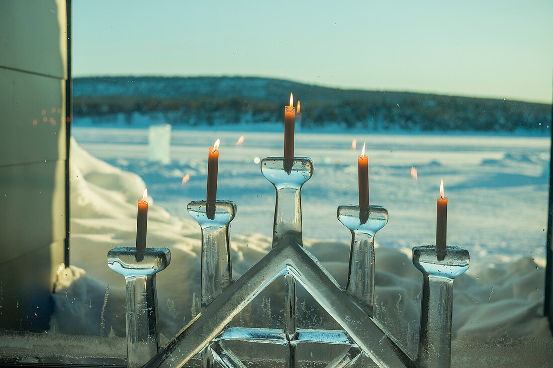 Ein Fenster mit Kerzen in einem Eiskerzenhalter im ICEHOTEL 365, das 2016 eingeführt wurde und eine permanente Struktur darstellt, die das ganze Jahr über den Aufenthalt im Eishotel in Jukkasjarvi bei Kiruna im schwedischen Lappland bietet. Nordschweden.