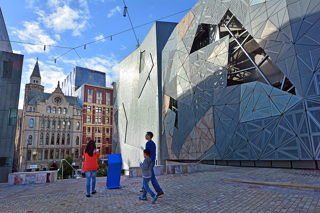 MELBOURNE - 13. APRIL 2014: Asiatische Familie spaziert neben dem ACMI-Gebäude vom Federation Square, der Heimat wichtiger kultureller Attraktionen und Weltklasse-Events in Melbourne Victoria, Australien.