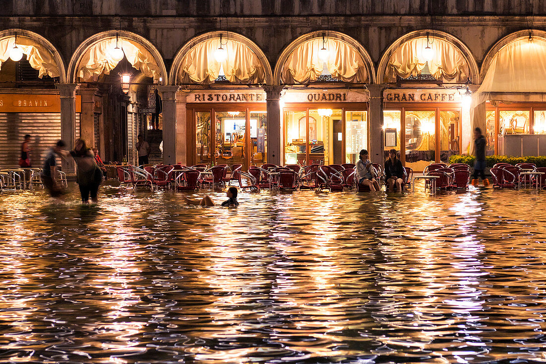 Menschen, die in der Flut am Markusplatz, Venedig, Venetien, Italien gehen und schwimmen