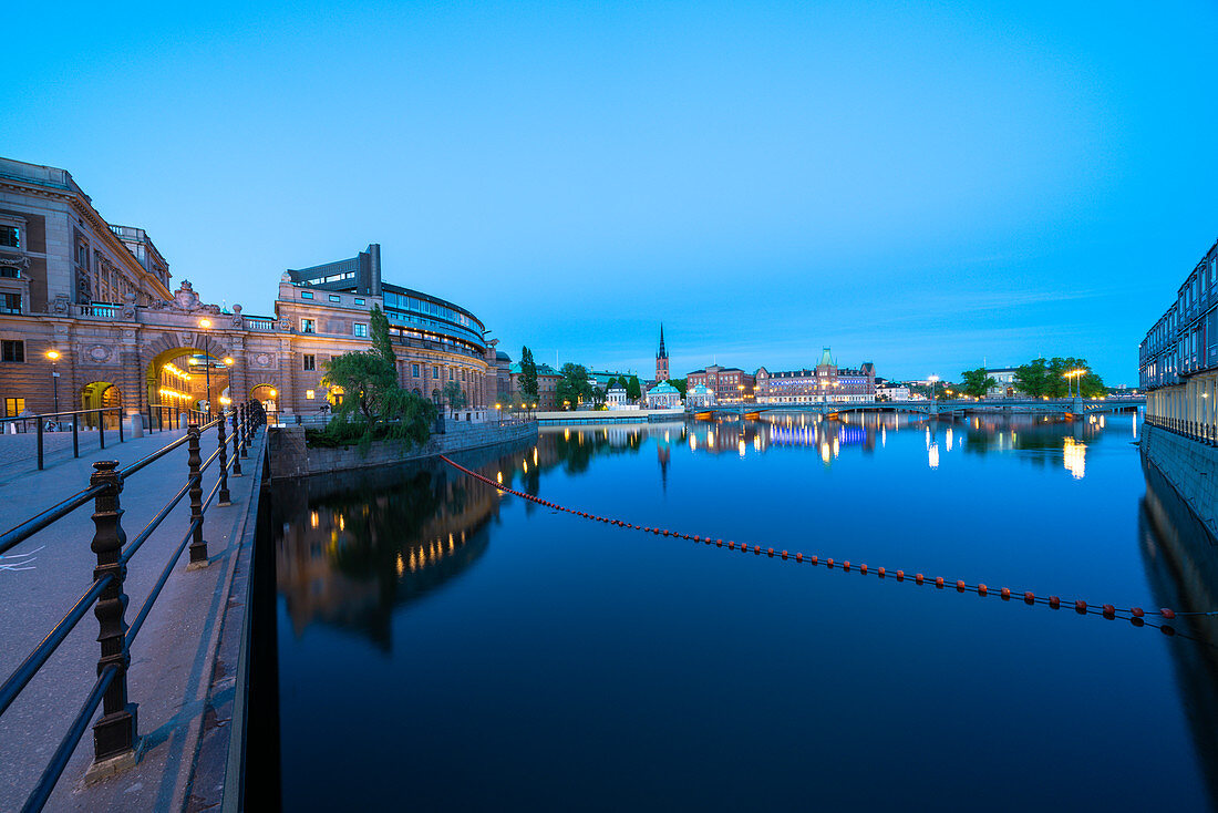 Abenddämmerung über dem Parlamentsgebäude (Riksdagshuset) und der Riksbron-Brücke entlang des Flusses Norrstrom, Stockholm, Schweden