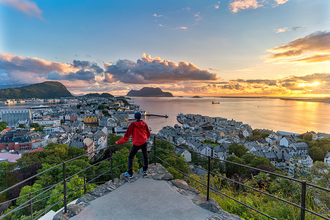 Rear view of man admiring sunset over the ocean and Alesund from Strykejernet viewpoint, More og Romsdal county, Norway