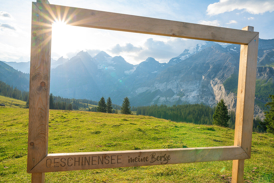 Holzbeschilderung auf grüner Wiese umrahmt die Schweizer Alpen am Oeschinensee, Berner Oberland, Kandersteg, Kanton Bern, Schweiz