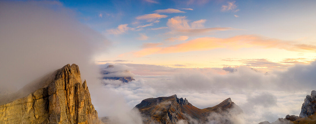 Aerial panoramic of Lastoi De Formin, Mondeval and Monte Pelmo emerging from clouds at sunset, Giau Pass, Dolomites, Veneto, Italy
