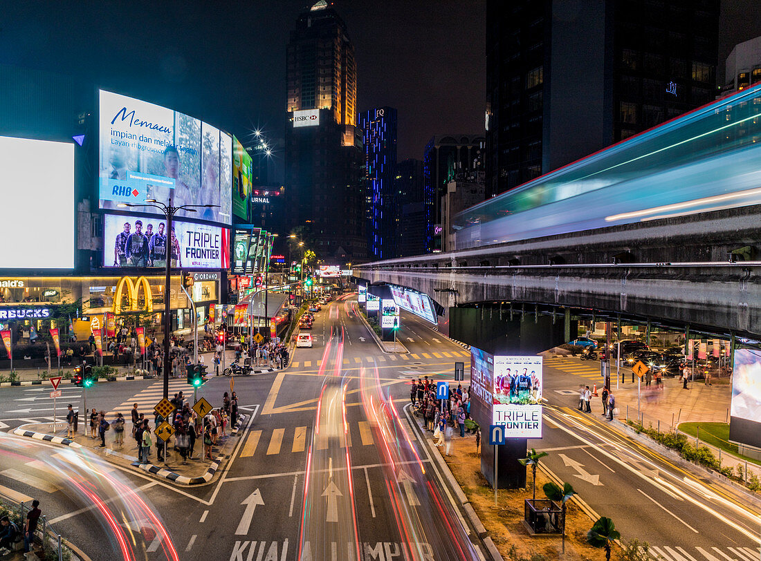 Nachtstraßenszene in Bukit Bintang mit einer vorbeifahrenden KL Monorail in Kuala Lumpur, Malaysia, Südostasien, Asien