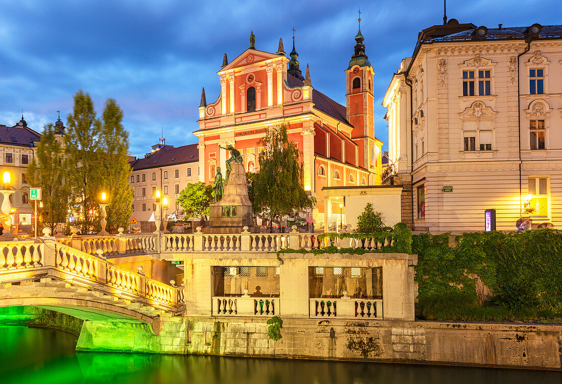 Die rosa Franziskanerkirche und die Dreifachbrücke (Tromostovje) über den Fluss Ljubljanica bei Nacht, Ljubljana, Slowenien, Europa