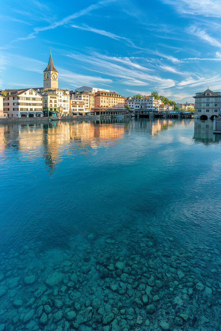Clock tower of St. Peter church mirrored in the turquoise water of Limmat River, Lindenhof, Zurich, Switzerland, Europe