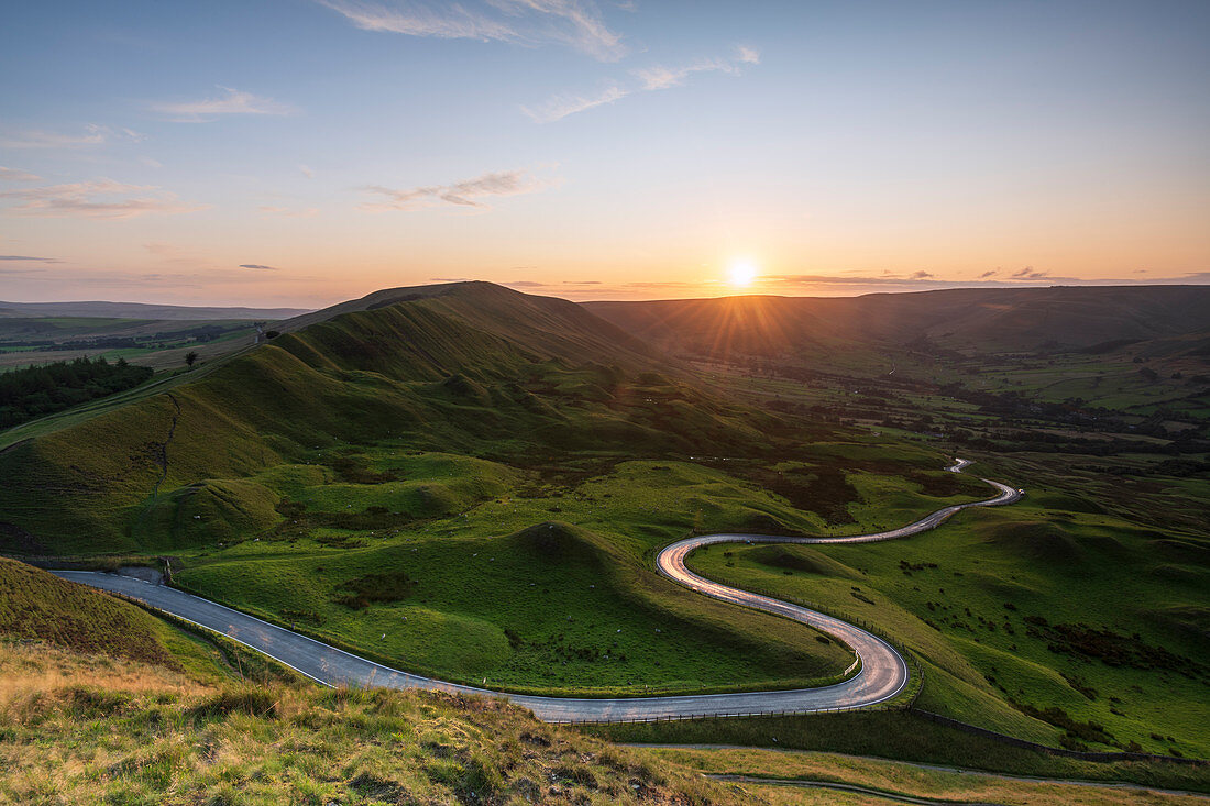 Long and winding rural road leading through green hills in the Peak District, with Rushup Edge, Peak District National Park, Derbyshire, England, United Kingdom, Europe