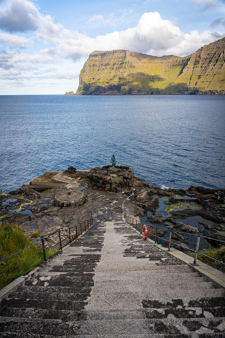View down the stairs to the bronze statue of the seal woman, created after the folk tale in which the village of Mikladalur was cursed, Mikladalur, Kalsoy, Faroe Islands, Denmark.
