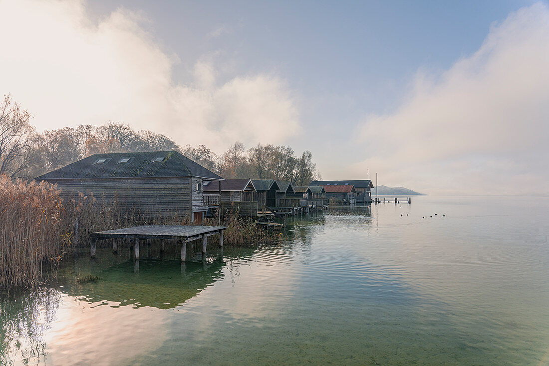 View from the jetty in Percha to boathouses on Lake Starnberg to the south towards the mountain, Starnberg, Bavaria, Germany.