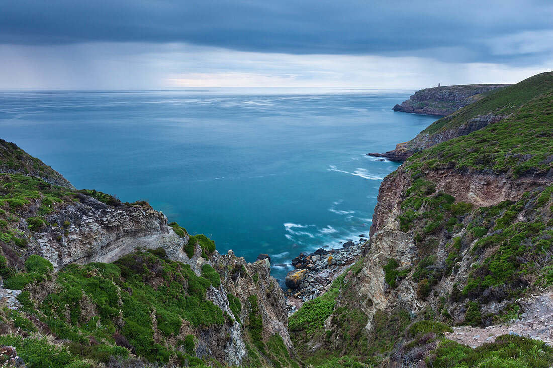 Regenwolken ziehen über das Meer und färben das Wasser tief Blau, Cap Frehel, Bretagne, Frankreich