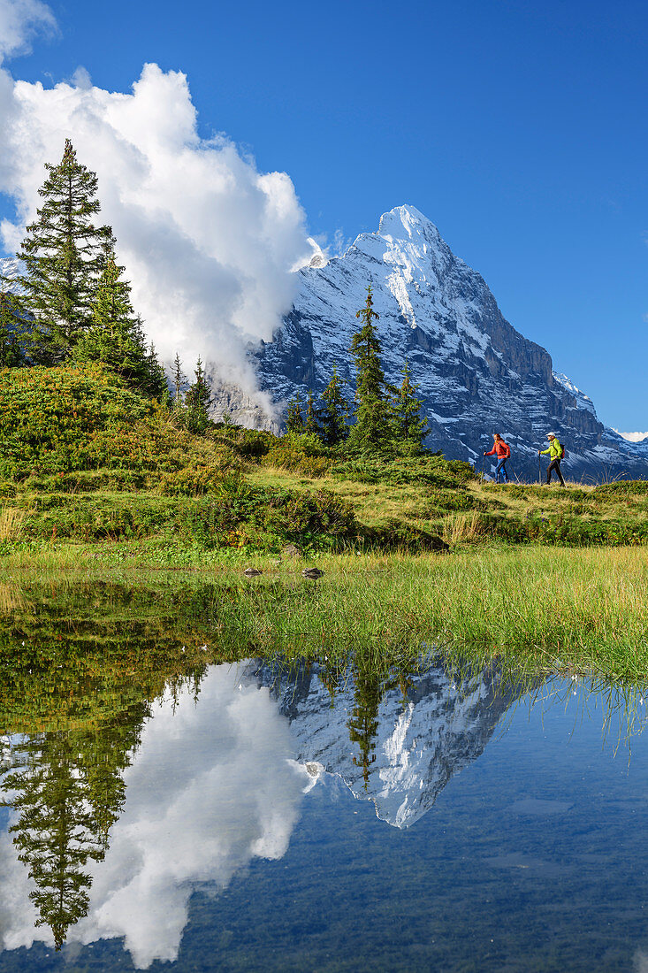 Mann und Frau beim Wandern an Bergsee, Eiger im Hintergrund, Berner Oberland, UNESCO Weltnaturerbe Schweizer Alpen Jungfrau-Aletsch, Berner Alpen, Bern, Schweiz