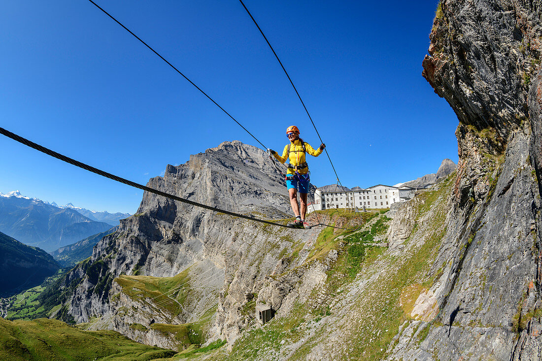 Frau am Erlebnisklettersteig Gemmi geht über Seilbrücke, Daubenhorn im Hintergrund, Gemmi, Berner Alpen, Wallis, Schweiz