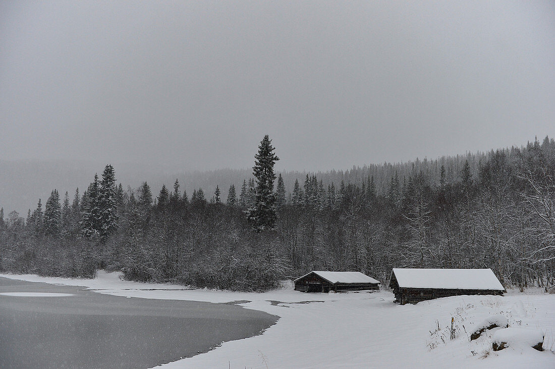 Two wooden huts by the lake in deep snow, Storjola, Borgafjäll, Lapland, Sweden