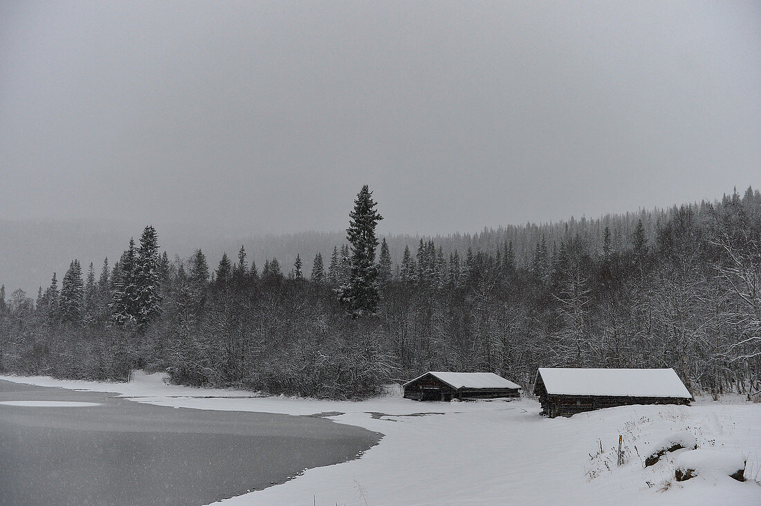 Zwei Holzhütten am See im tiefen Schnee, Storjola, Borgafjäll, Lappland, Schweden