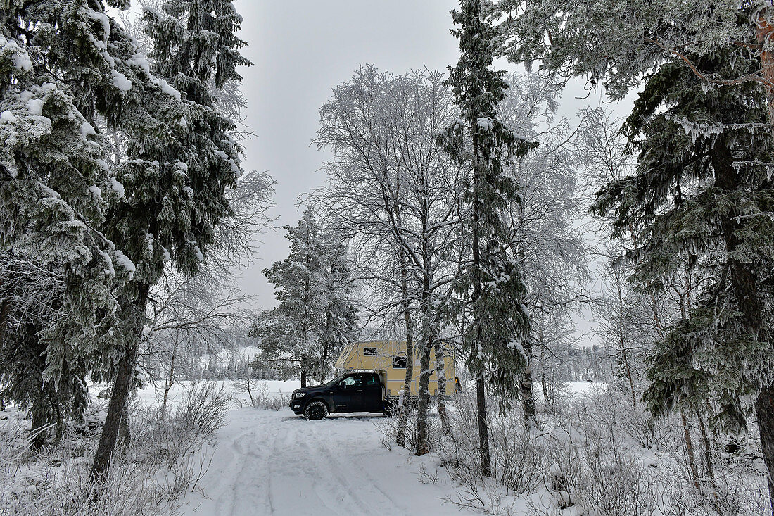 Ein Wohnmobil parkt in der Winterlandschaft am See, Storuman, Västerbottens Län, Schweden