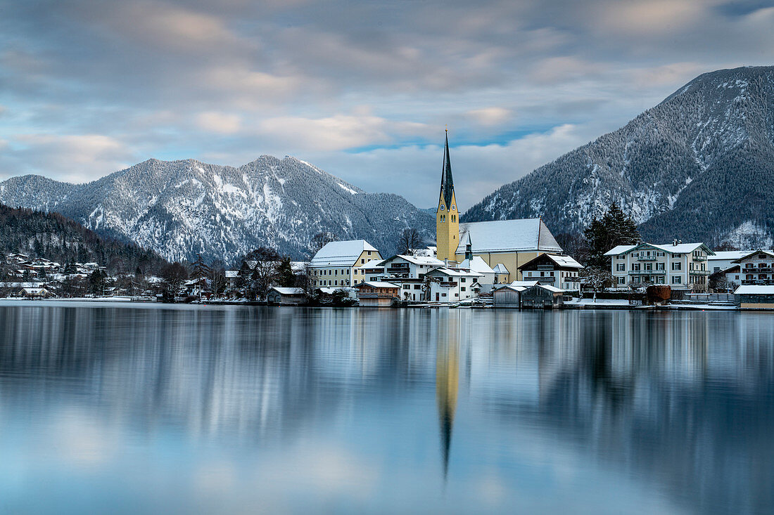 Blick über den winterlichen Tegernsee auf die Ortschaft Rottach-Egern mit der Kirche Sankt Laurentius, Bayern, Deutschland.