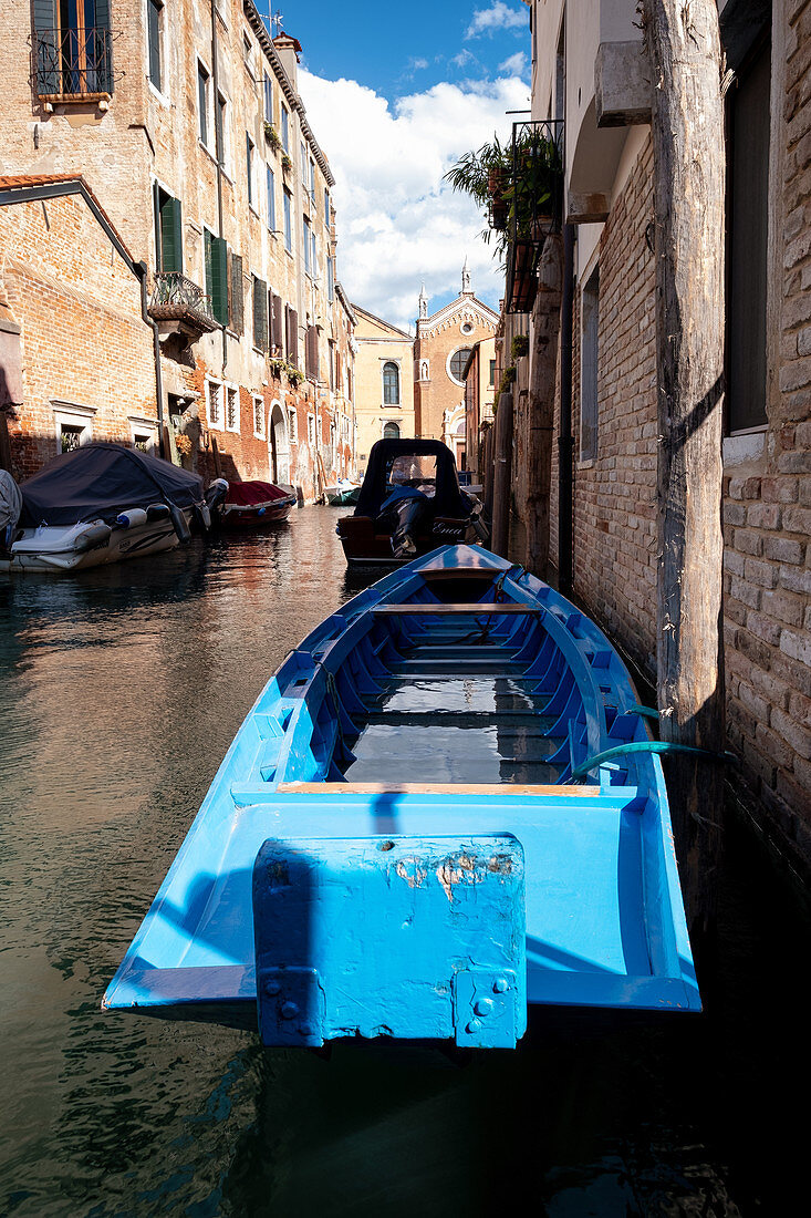 Blick auf ein blaues Boot entlang eines Kanals, im Hintergrund Madonna dell'Orto, Cannaregio, Venedig, Venetien, Italien, Europa