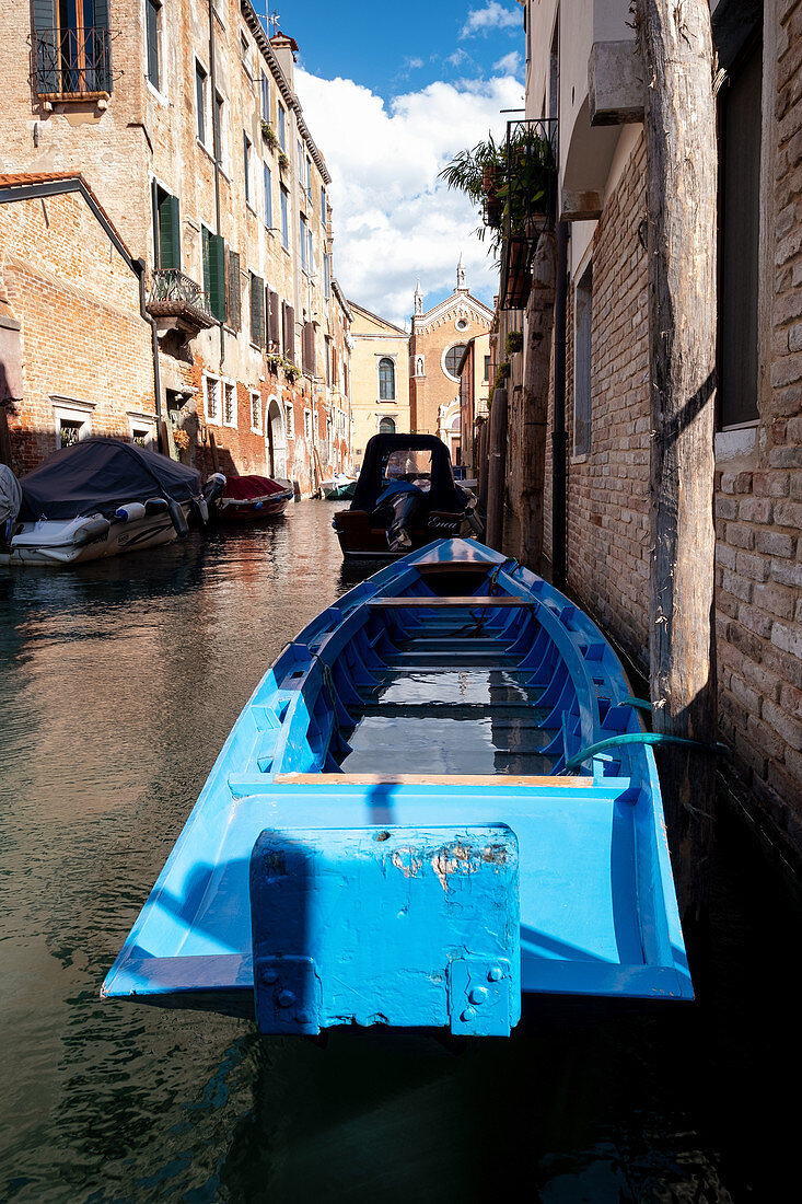 View of a blue boat along a canal, in the background Madonna dell'Orto, Cannaregio, Venice, Veneto, Italy, Europe