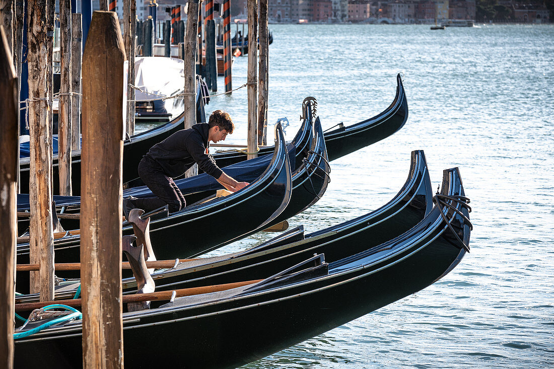 Blick auf einen Gondoliere bei der Reinigung seiner Gondel  am Canale Grande, Venedig, Venetien, Italien, Europa