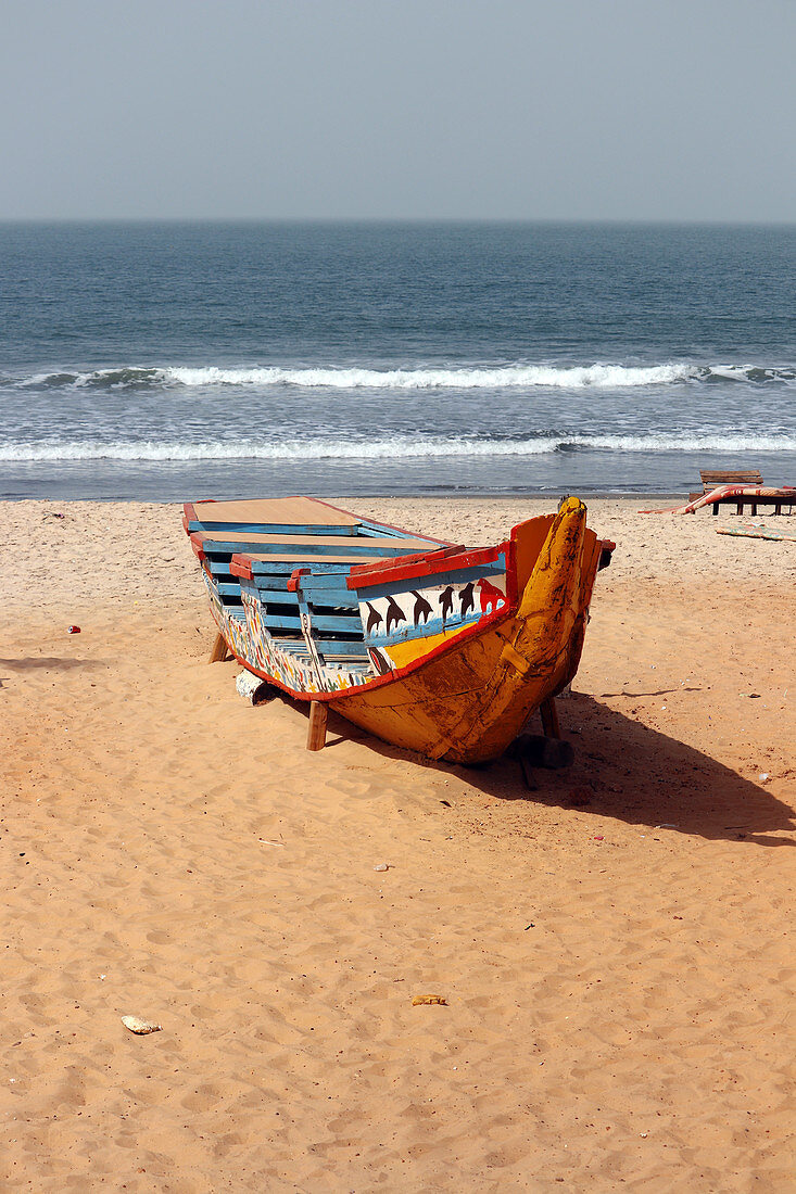 Gambia; Capital Region Banjul; Kotu Beach near Serekunda; brightly painted fishing boat on the beach