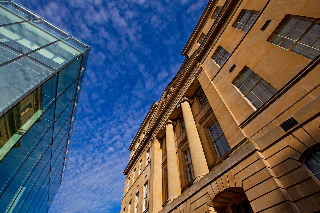 Juxtaposition of a modern glass building and a classic, columned building. Bath, United Kingdom