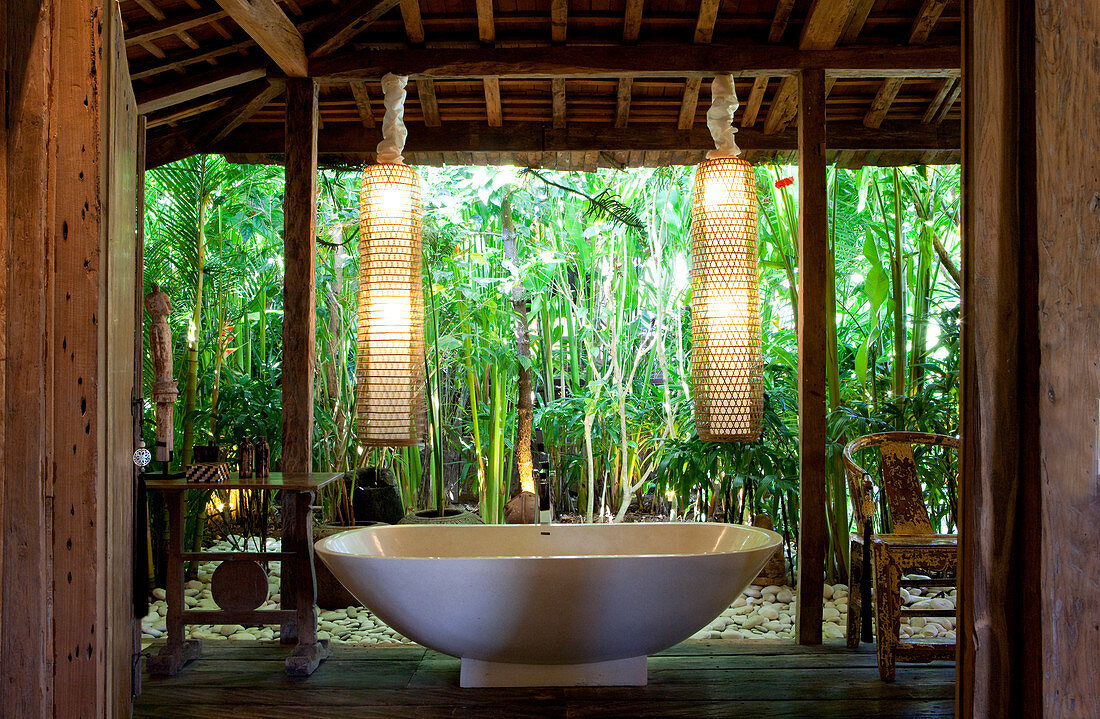 Freestanding bathtub inside an open bathroom in an old wooden house in Bali. Bali, Indonesia.