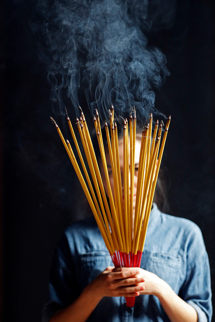 Young Chinese woman praying with big burning incense sticks in her hands, Ha Chuong Hoi Quan Pagoda, Ho Chi Minh City, Vietnam, Indochina, Southeast Asia, Asia