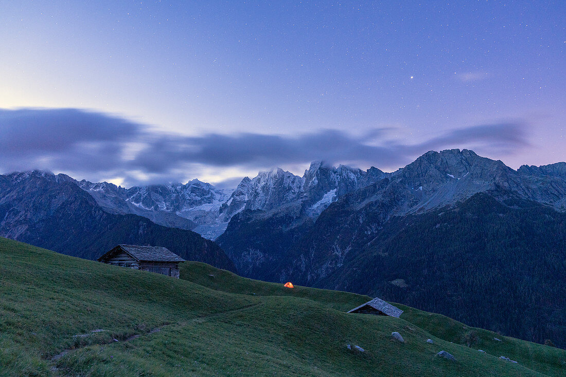 Stars over tent and huts overlooking Piz Badile and Piz Cengalo, Tombal, Soglio, Valbregaglia, Canton of Graubunden, Switzerland, Europe