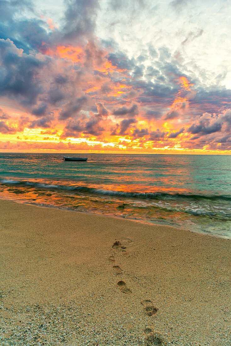 Afrikanischer Sonnenuntergang über Fußabdrücken auf tropischem Sandstrand, Le Morne Brabant, Schwarzer Fluss, Mauritius, Indischer Ozean, Afrika